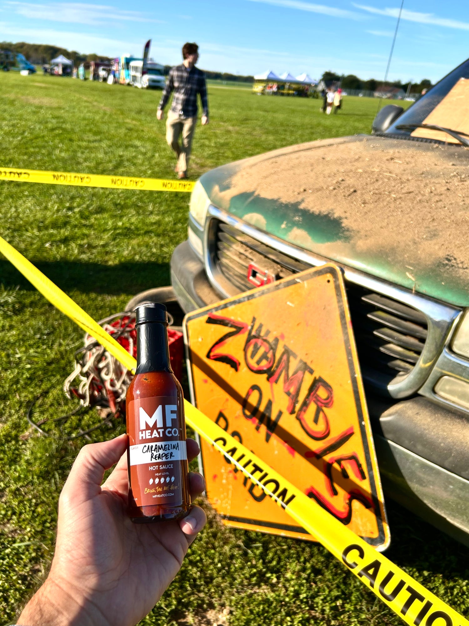 Hand holding hot sauce bottle at Zombie Fest
